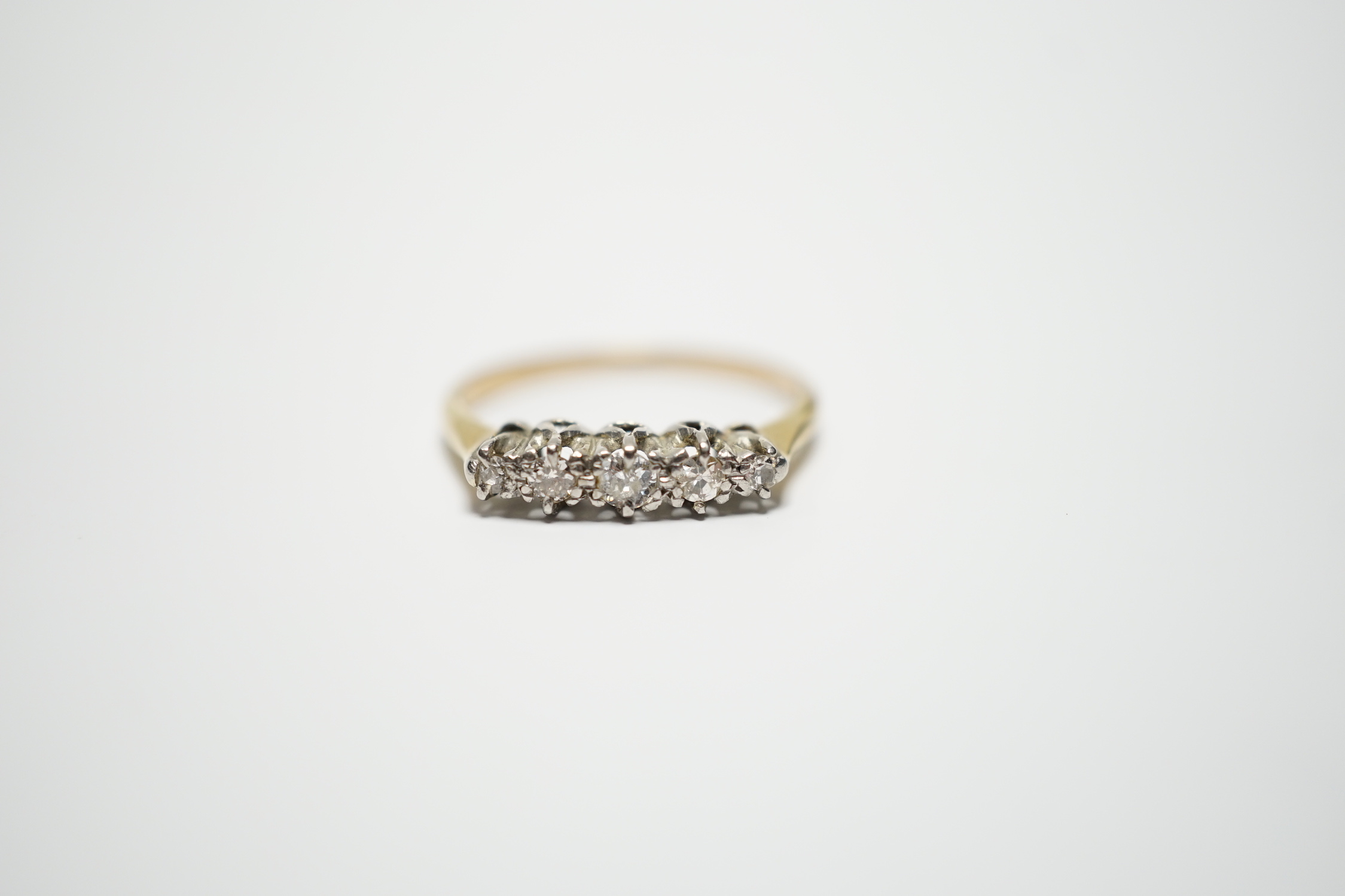 A yellow metal and graduated five stone diamond set half hoop ring, size M, gross weight 2 grams.